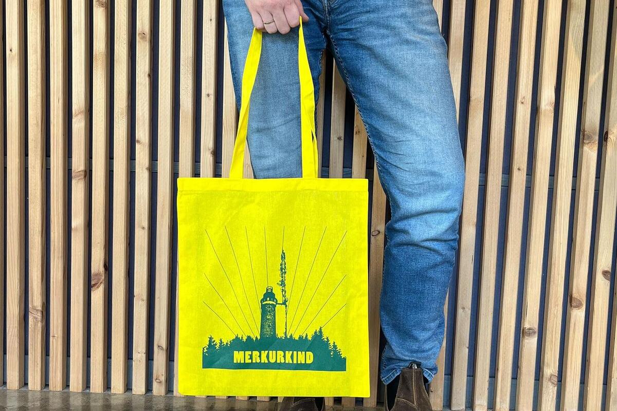 Mann, der eine gelbe Merkurkind-Stofftasche trägt